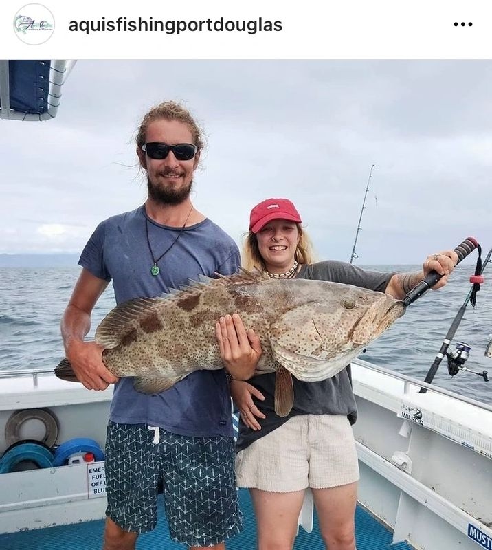 a man holding a fish on a boat posing for the camera