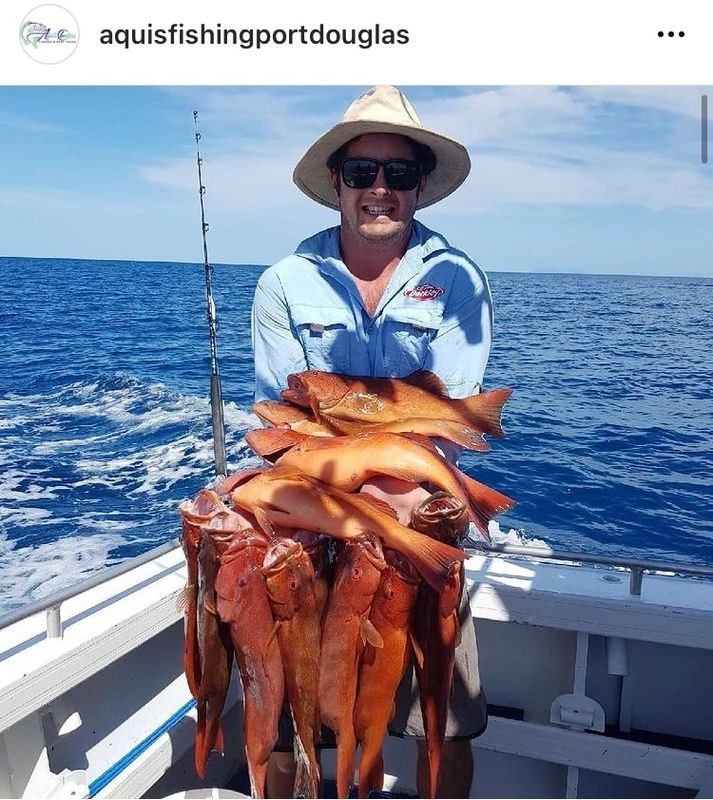 a man holding a fish on a boat in a body of water